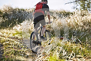 Attractive cyclist riding the bicyclist on the beautiful summer mountain trail.