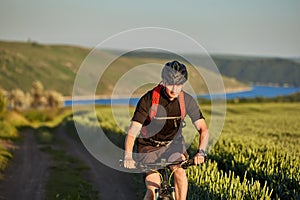 Attractive cyclist riding mountain bicyclist in the summer green field.