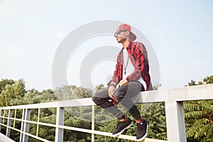 Attractive dark skinned young boy sitting against nature background