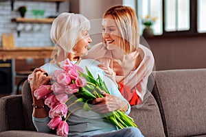 Attractive daughter tenderly looking at elderly d smiling mother