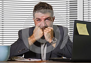 Attractive depressed and frustrated businessman working at office computer desk desperate and overwhelmed with financial business