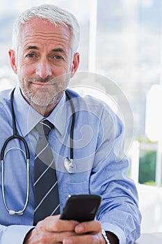 Attractive doctor using his smartphone