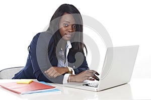 Attractive and efficient black ethnicity woman sitting at office computer laptop desk typing