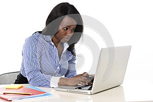 Attractive and efficient black ethnicity woman sitting at office computer laptop desk typing