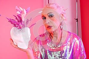 Attractive elderly female person demonstrating flower pot