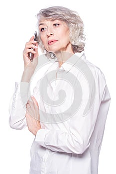 An attractive elderly woman listens very attentively to the interlocutor during a telephone conversation using a photo