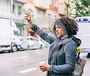 Attractive and elegant African American woman raises her hand to catch a taxi