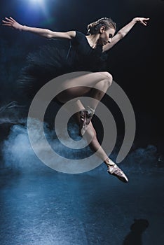 attractive elegant ballet dancer in pointe shoes and black tutu in studio