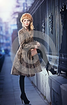 Attractive elegant blonde young woman wearing an outfit with Russian influence in urban fashion shot. Beautiful fashionable girl