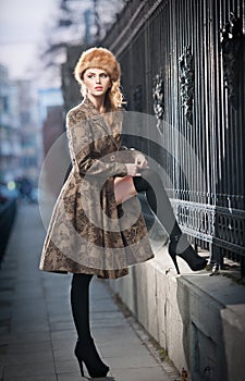 Attractive elegant blonde young woman wearing an outfit with Russian influence in urban fashion shot. Beautiful fashionable girl