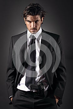 Attractive and elegant man posing with a gun in his trousers