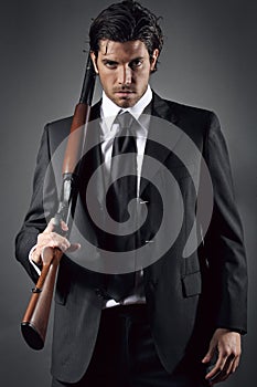 Attractive and elegant man posing with shotgun