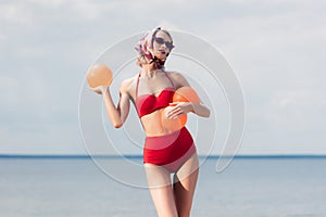 attractive elegant woman in red trendy bikini sunglasses and silk scarf posing with balls