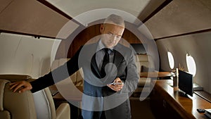 Attractive entrepreneur with smartphone inside of private jet.