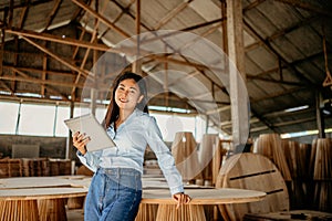 attractive entrepreneurial woman using a computer tablet in woodworking workshop
