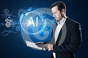 Attractive european businessman using tablet with glowing AI hologram on blue background. Artificial intelligence, robotics