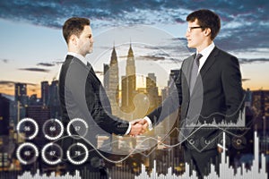 Attractive european businessmen shaking hands with creative glowing business graph on blurry city background. Innovation, teamwork