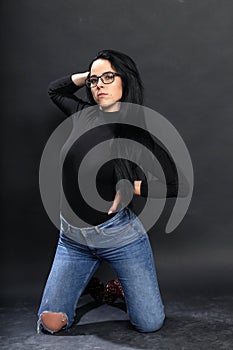 Attractive european girl with black hair and glasses posing in studio on isolated background. Style, trends, fashion concept.