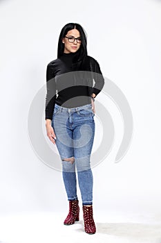 Attractive european girl with black hair and glasses posing in studio on isolated background. Style, trends, fashion concept.