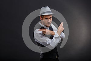 An attractive guy, in a retro suit and hat, crossed his arms showing two fingers.