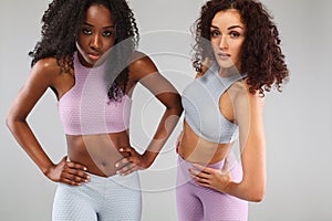 Two fitness women in sportswear isolated over gray background. Sport and fashion concept with copy space.