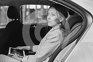 Attractive executive female manager working with a tablet in a backseat of a car