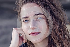 Attractive face of a young woman with wavy hair. Blue eyes, black eyebrows, a smile