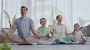 Attractive family with children doing yoga indoors