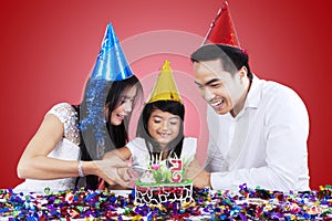 Attractive family cutting a birthday cake