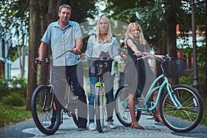 Attractive family dressed in casual clothes on a bicycle ride with their cute little spitz dog.