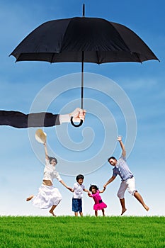 Attractive family jumping at field under umbrella