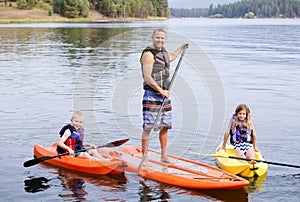 Attractive family kayaking and paddle boarding together on a beautiful lake