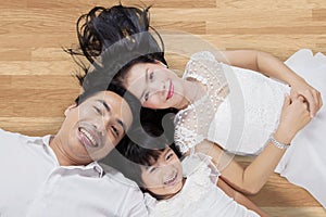 Attractive family lying on wooden floor