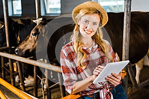 attractive farmer in straw hat holding tablet and looking at camera