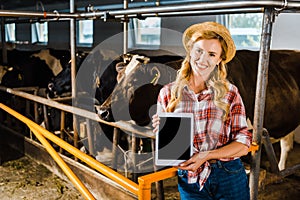 attractive farmer in straw hat showing tablet with blank screen