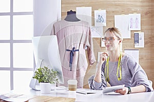 Attractive fashion designer working in office, leaning on desk,