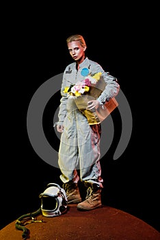 attractive female astronaut in spacesuit with helmet and flowers in paper bag standing