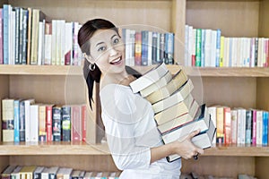 Attractive female bring stack of books in library