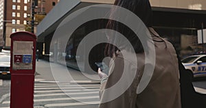 Attractive female brunette using navigation on smartphone and crossing streets of urban New York City