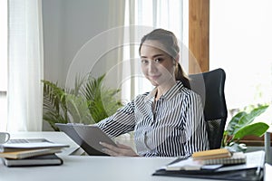 Attractive female business leader working at modern workplace and looking confidently to camera