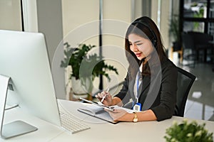 Attractive female customer service representatives wearing headset working on support hotline in modern workplace