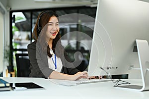 Attractive female customer service representatives wearing headset working on support hotline in modern workplace