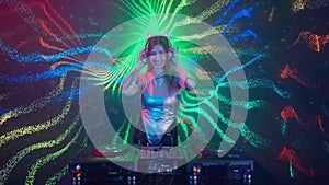 Attractive female on digital wall colorful visual graphic background. Young woman dj dancing, plays music on turntables