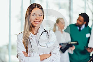 Attractive female doctor on hospital corridor looking at camera smiling