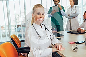 Attractive female doctor on hospital looking at camera smiling