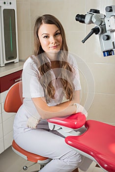 Attractive female doctor with microscope in the modern dentist office