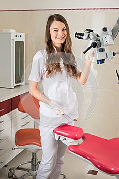 Attractive female doctor with microscope in the modern dentist office