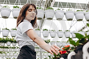 Attractive female florist working in garden centre. Starting saling flowerpots