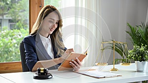 Attractive female lawyer in formal suit reading something on her notebook in the office