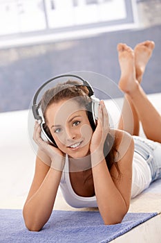 Attractive female listening music laying on floor